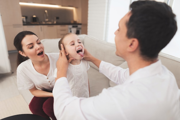 Le médecin en blouse blanche vérifie la gorge d'une fille malade.