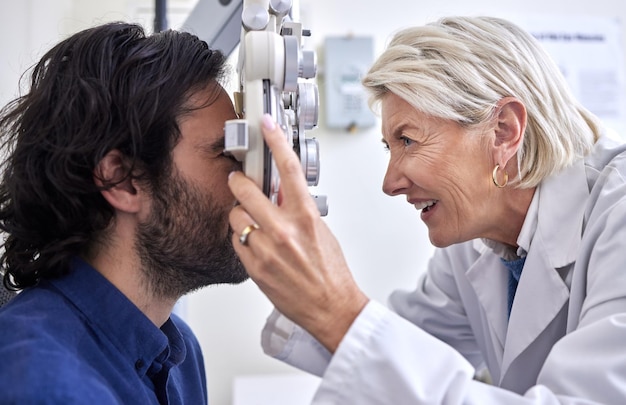 Médecin avec un client en test de vision ou examen de la vue par un optométriste ou un ophtalmologiste senior Heureux opticien aidant à vérifier la santé de la rétine d'un patient ou d'un client avec une assurance médicale