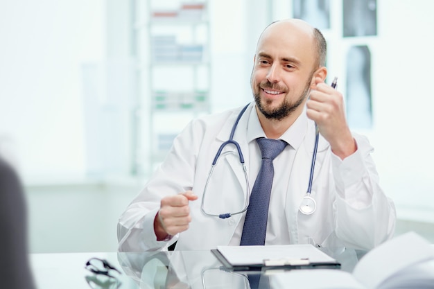 Médecin compétent avec un stéthoscope assis à son bureau