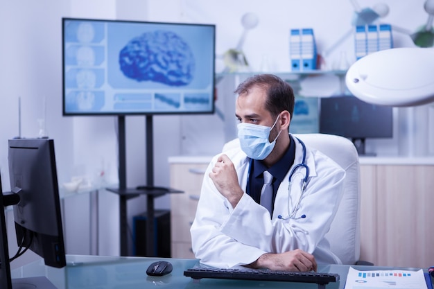 Médecin concentré sur son travail au cabing avec sa bouche couverte. Médecin avec masque de protection.