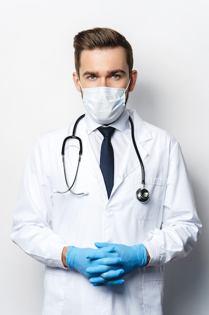 Médecin confiant avec le stéthoscope portant un masque de prévention et des gants en latex