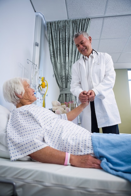 Médecin consolant un patient senior en salle