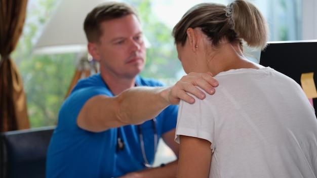 Le médecin console le patient avec un diagnostic dangereux à son bureau dans la clinique un médecin de sexe masculin a mis sa main