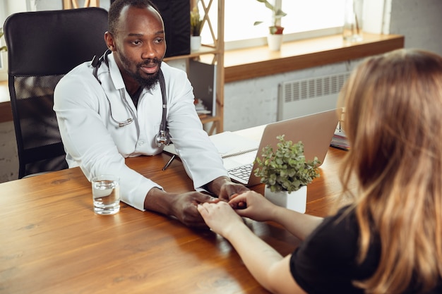 Médecin consultant pour une patiente au cabinet. Médecin afro-américain lors de son travail avec les patients, expliquant des recettes de médicaments. Un travail acharné quotidien pour la santé et sauver des vies pendant l'épidémie.