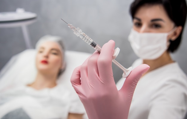 Le médecin cosmétologue effectue la procédure d'injections faciales.