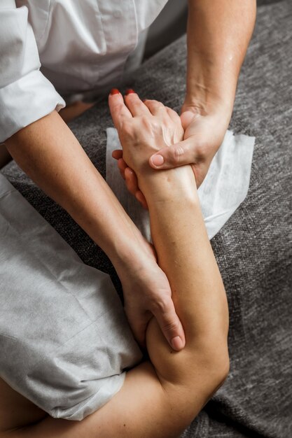 Médecin cosmétologue esthéticienne masse les mains de sa cliente