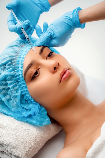 Le médecin cosmétologue réalise la procédure d’injections faciales rajeunissantes pour resserrer et lisser les rides sur la peau du visage d’une femme dans un salon de beauté. Cosmétologie soins de la peau