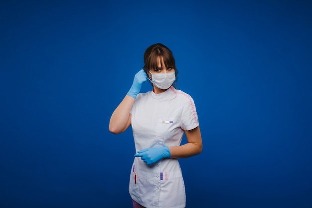 Médecin dans un masque de protection et des gants en caoutchouc sur fond bleu