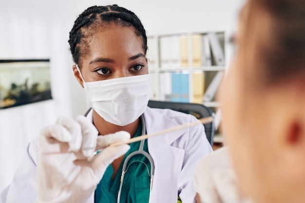 Médecin demandant au patient d'ouvrir la bouche