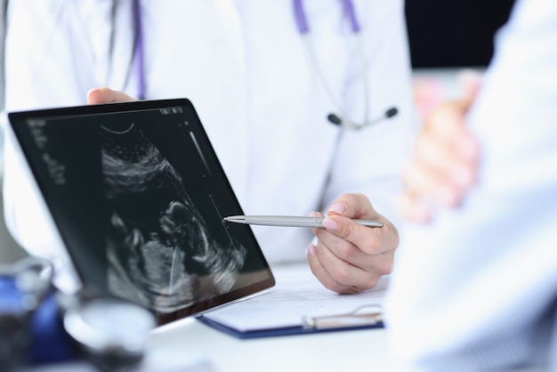 Le médecin démontre l'échographie fœtale sur l'écran de la tablette. Examen médical pendant la grossesse