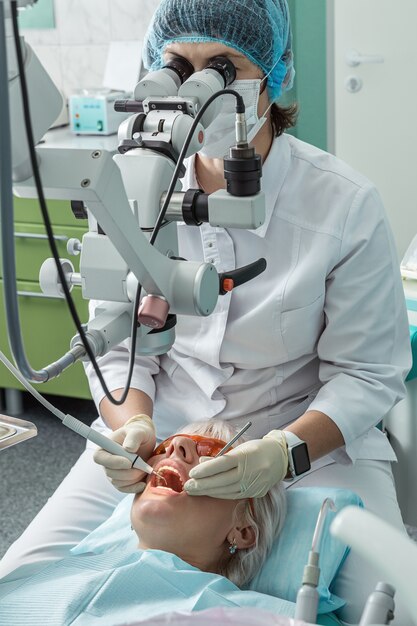 Le médecin dentaire examine le patient à l'aide d'un microscope.