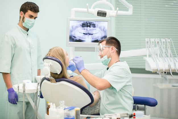Un médecin dentiste avec un assistant travaille dans une clinique dentaire.