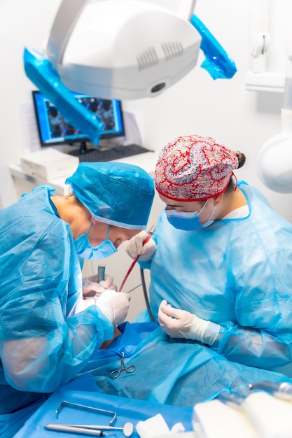 Médecin dentiste de la clinique dentaire et l'assistant avec des costumes bleus effectuant une opération d'un implant