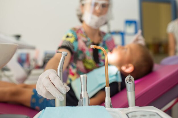 Le médecin dentiste des jeunes enfants traite les dents avec différents appareils