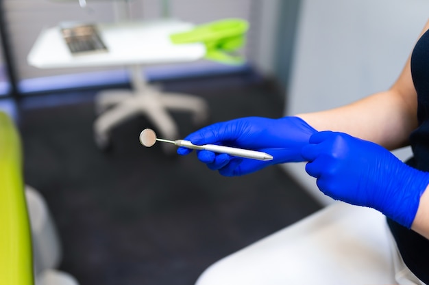 Médecin dentiste avec miroir dans les mains met des gants.