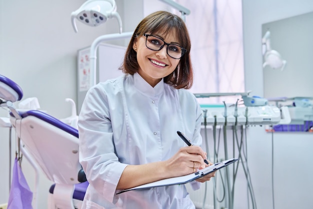 Médecin dentiste parlant regardant une webcam faisant une conférence téléphonique vidéo dans un cabinet dentaire