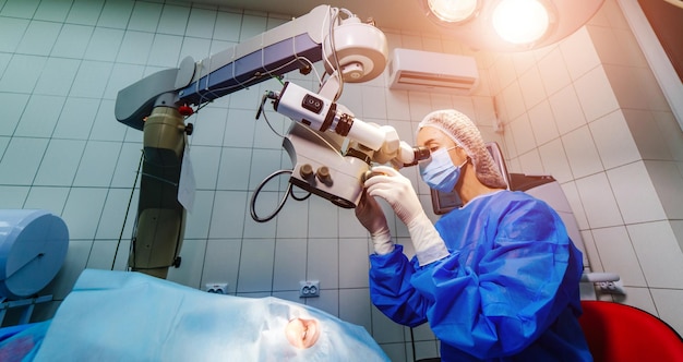 Médecin dentiste utilisant un microscope dentaire dans un bureau de stomatologie moderne pour le fonctionnement d'un patient