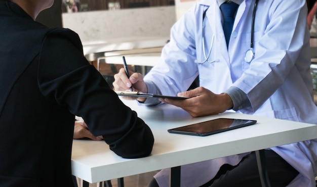 médecin docteur explique le diagnostic à l&#39;équipe de médecin tenant et montrant le presse-papiers explorant un document important.