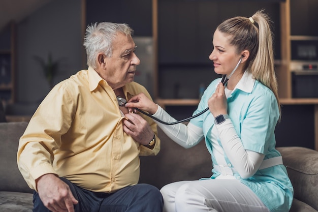 Le médecin à domicile rend visite à un homme âgé pour vérifier sa santé.