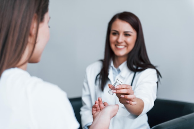 Un médecin donne des médicaments au patient Une jeune femme rend visite à une femme médecin dans une clinique moderne