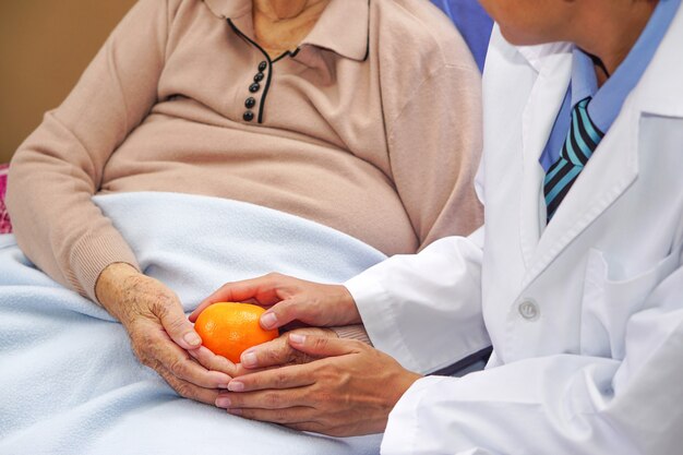 Le médecin a donné une orange à la vieille dame asiatique âgée ou âgée