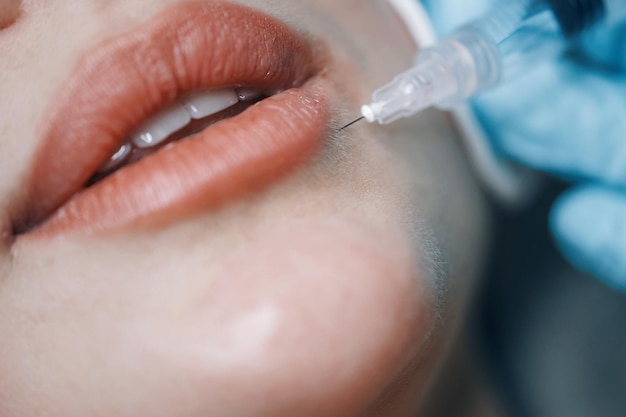 Le médecin du studio de beauté procède à des injections cosmétiques dans la peau du visage d'un jeune patient