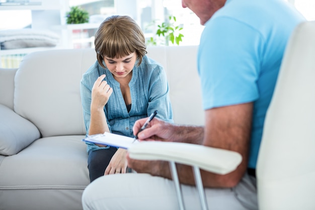 Médecin écrivant sur le bloc-notes en consultant une patiente