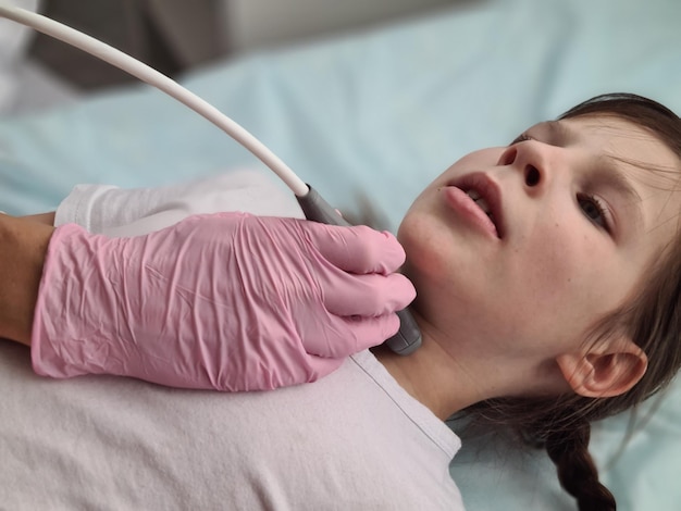 Médecin effectuant une échographie thyroïdienne fille médecin spécialiste examinant l'enfant nca
