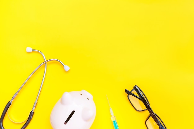 Médecin équipement stéthoscope tirelire verres isolés sur tableau jaune