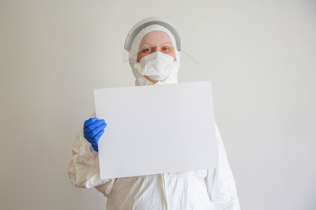 Le médecin est une femme d'âge moyen à lunettes, combinaison de protection et masque avec un drap blanc à la main