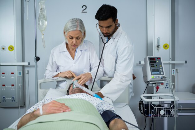 Médecin et examen d'un patient avec stéthoscope et placement d'un masque à oxygène