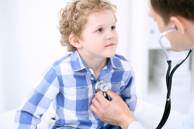 Médecin examinant un enfant patient par stéthoscope