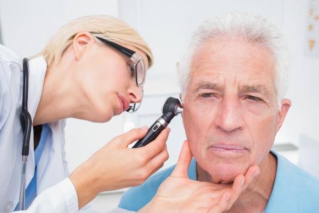 Médecin examinant l&#39;oreille des patients âgés avec otoscope