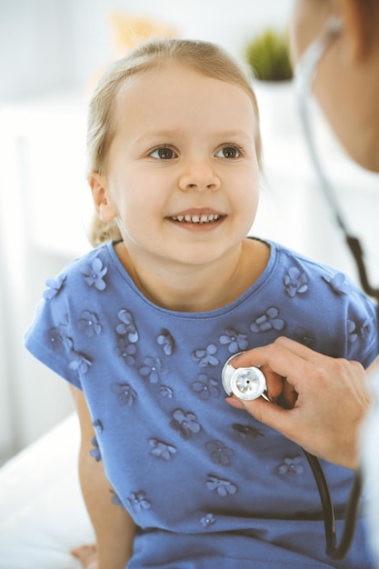 Médecin examinant une petite fille au stéthoscope Heureux enfant patient souriant à l'inspection médicale habituelle Concepts de médecine et de soins de santé