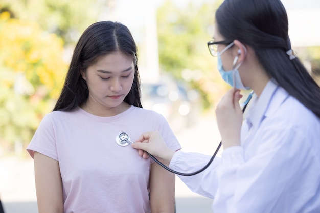 Un médecin examine une patiente avec un stéthoscope dans un parc d'été.