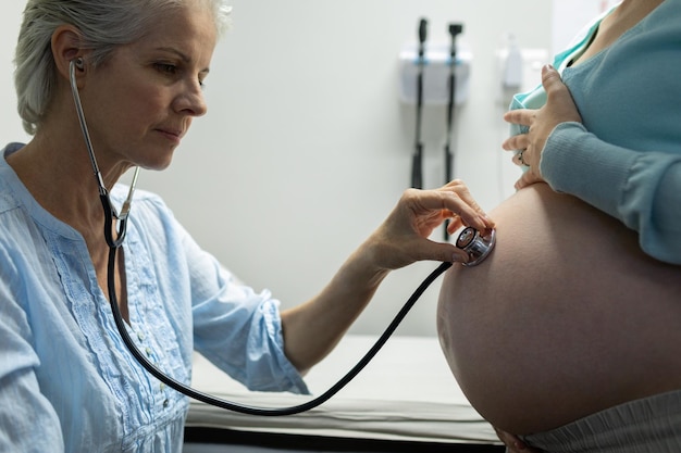 Photo un médecin examine le ventre d'une femme enceinte avec un stéthoscope