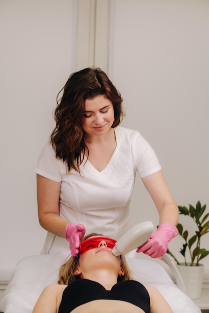 Un médecin fait une épilation au laser pour un client de poils faciaux indésirables dans un salon de beauté