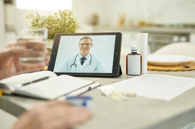 Médecin de famille amical apparaissant sur l'écran de la tablette lors d'un appel vidéo