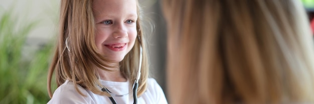 Le médecin de famille laisse sa jeune patiente jouer avec le concept de stéthoscope des soins de santé pour enfants et