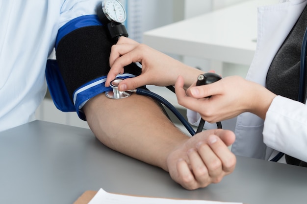 Médecin féminin mesurant la pression artérielle au patient. Les mains se resserrent. Concept médical et de soins de santé