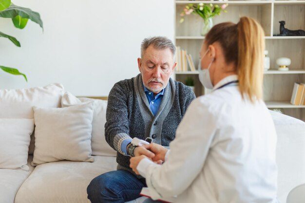 Médecin femme homme âgé prenant sa pression artérielle au cabinet du médecin ou à la maison vieil homme patient et