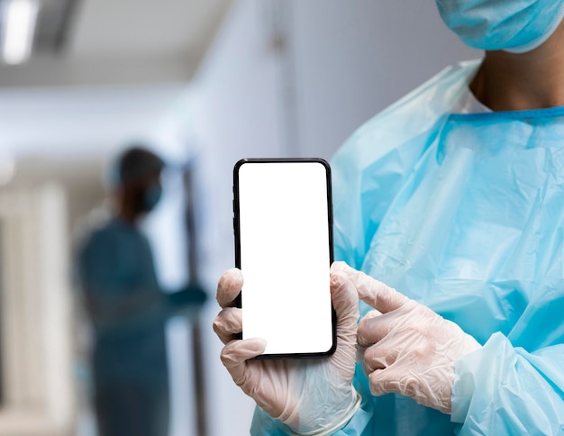 Photo médecin femme en vêtements de protection pointant vers un smartphone