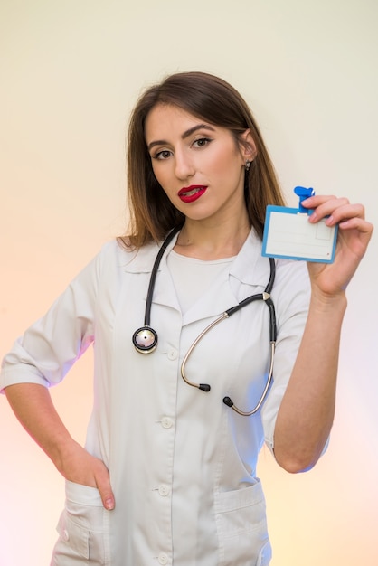 Médecin gai et attrayant en uniforme médical posant avec stéthoscope et badge à l'hôpital