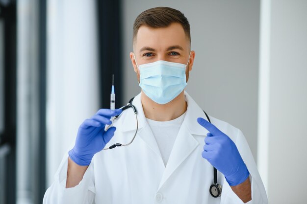 Un médecin en gants bleus tenant une bouteille de vaccin Gros plan Concept de médecine et de soins de santé