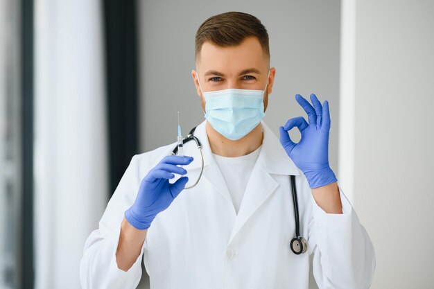 Un médecin en gants bleus tenant une bouteille de vaccin. Photo en gros plan. Concept de médecine et de soins de santé