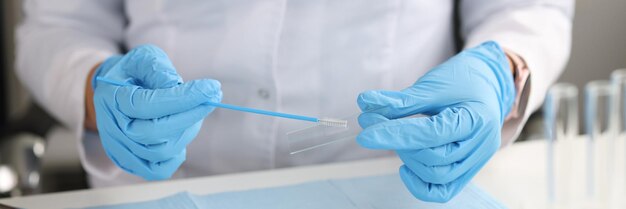 Médecin en gants tient une brosse pour les frottis et le verre dans le concept urogénital des cytobarils de laboratoire