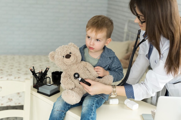 Médecin et garçon patient examinant l'ours en peluche à l'hôpital