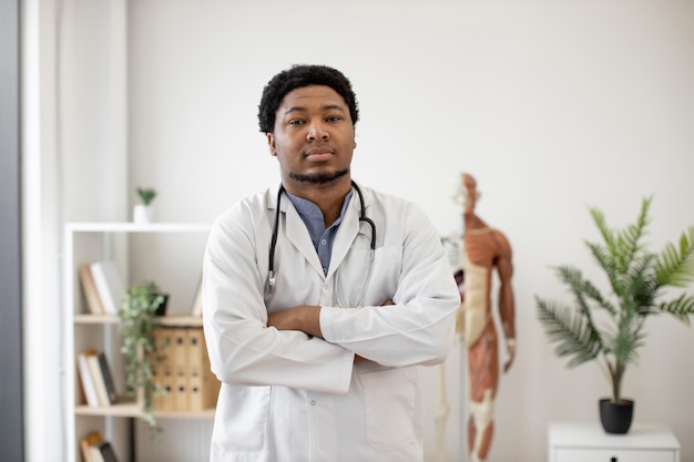 Médecin généraliste en blouse blanche posant dans le cabinet du médecin