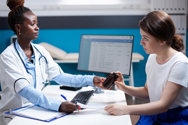 Médecin généraliste offrant une consultation clinique au patient. médecine. Spécialiste de la santé pendant le bilan de santé prescrivant des médicaments en flacon de pilules à une femme dans une clinique moderne