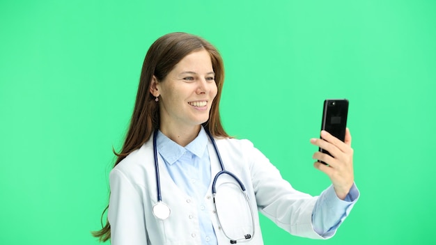 Médecin en gros plan sur un fond vert avec un téléphone